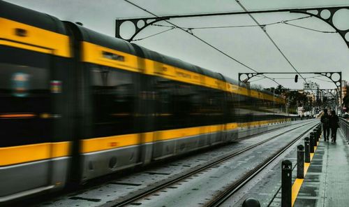 Train at railroad station in city against sky