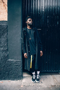 Young fashionable man looking away while leaning on wall