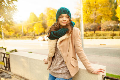 Thoughtful young woman leaning on railing by street