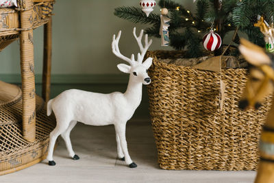 Christmas card, toy of a white deer in the decor of a house decorated for christmas