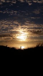 Silhouette man on field against sky during sunset