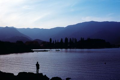 Scenic view of river and mountains against sky at sunset