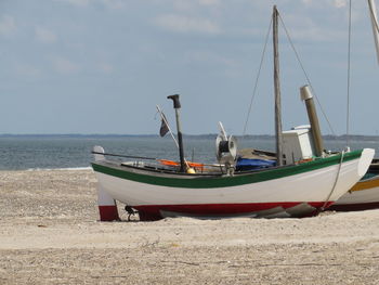 Sailboats moored on beach against sky