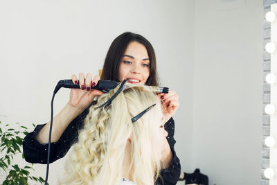 Young woman straightening hair at home