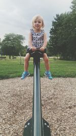 Portrait of girl sitting on seesaw at playground