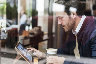 Usa, new york city, businessman sitting in coffee shop, using digital tablet