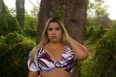 Portrait of young woman against tree trunk