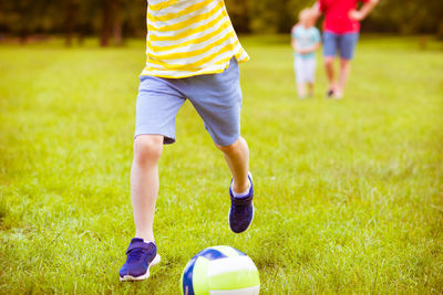 Low section of boy playing soccer on field