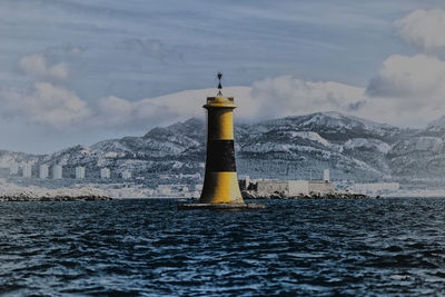 Lighthouse by sea against sky