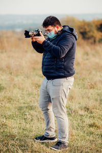 Man holding camera while standing on field