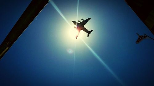 Low angle view of silhouette airplane against clear blue sky