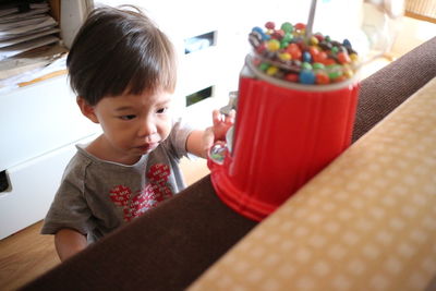 High angle view of boy looking at bucket with candies at home