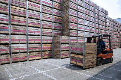 Worker on forklift moving crates on factory yard