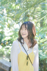 Portrait of young woman standing against trees