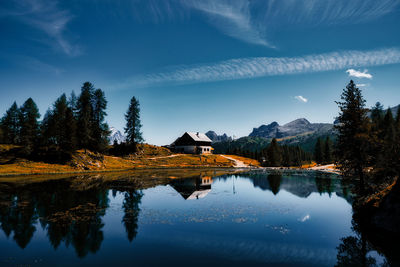 Reflection of trees and mountain shelter in lake against sky. lago federa