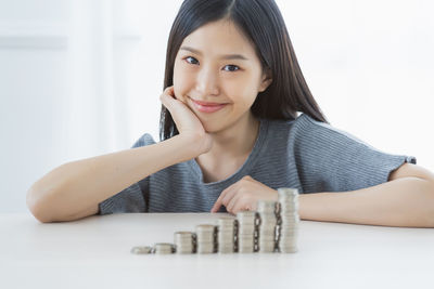 Portrait of smiling young woman by stacked coins