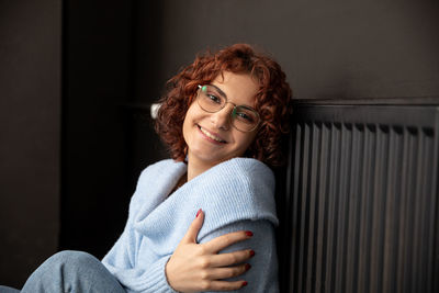 Portrait of young woman sitting on sofa at home