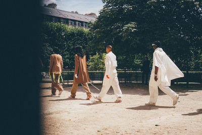 Rear view of people walking against trees