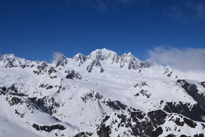 Scenic view of snow covered mountains against blue sky