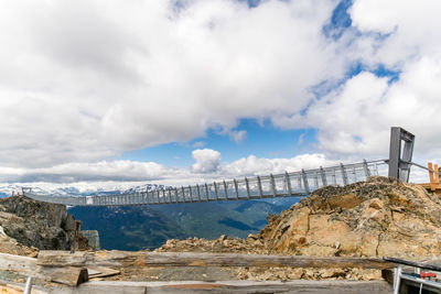 Bridge over mountain against cloudy sky