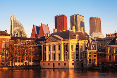 Canal by residential buildings in city against sky