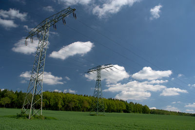 Low angle view of electricity pylon on field against sky