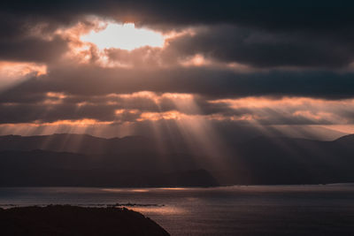 Scenic view of sea against dramatic sky during sunset