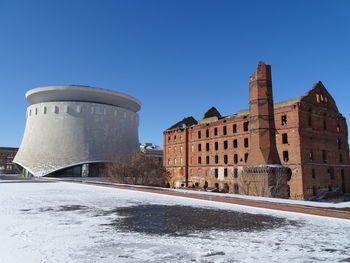 Snow covered buildings against clear blue sky