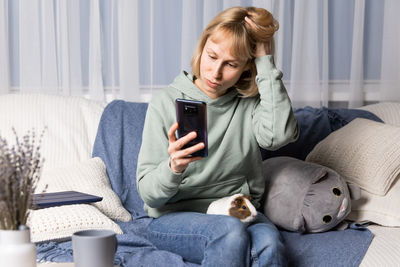 Young woman using phone while sitting at home