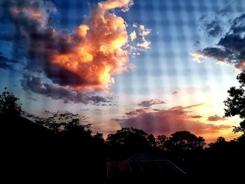 Low angle view of silhouette trees and buildings against sky during sunset