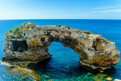 Rock formation in sea against blue sky