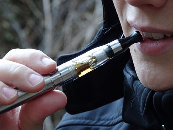 Cropped image of person smoking electronic cigarette