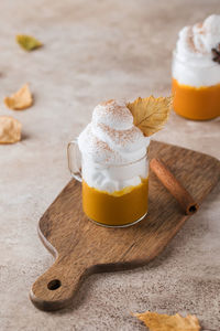 Mug of pumpkin coffee with whipped cream and dry leaf