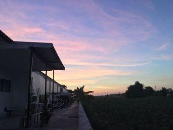 Road amidst buildings against sky during sunset