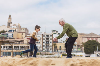 Happy boy running to hug his grandfather on the beach