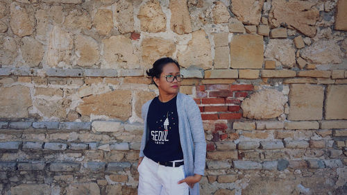 Young man standing against brick wall