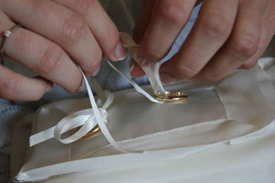 Cropped hands of woman tying gold rings