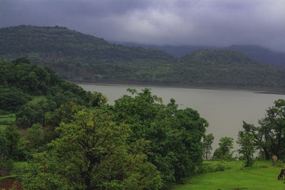 Scenic view of river by mountains against sky