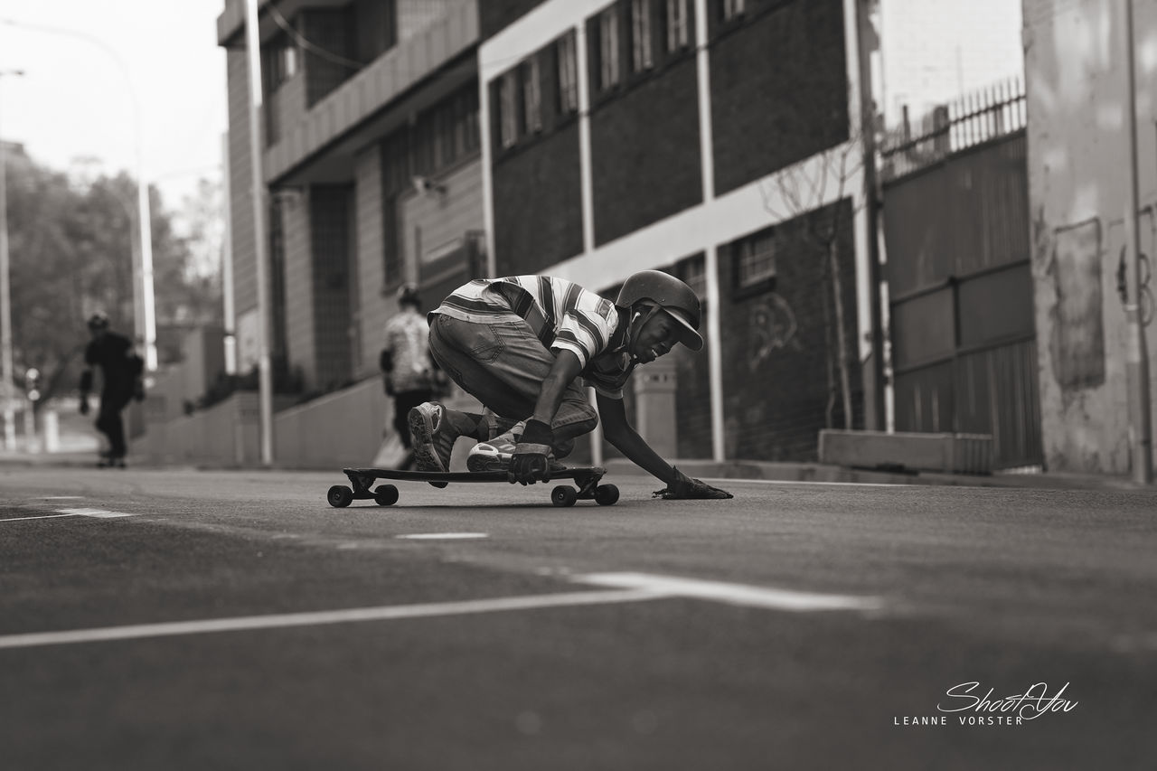 MAN SKATEBOARDING IN CITY