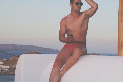 Midsection of shirtless man against sky