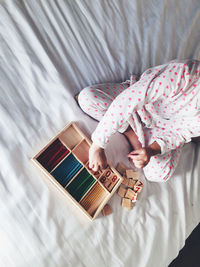 Low section of person arranging toy blocks in wooden box on bed