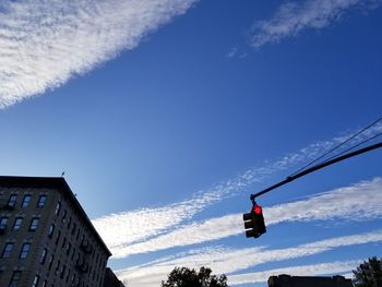 Low angle view of man hanging against blue sky