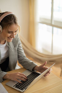 Young woman working at home with laptop on desk and headphones.  notebook for working. 