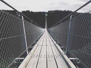 Footbridge against cloudy sky