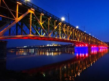 Illuminated bridge over river at night