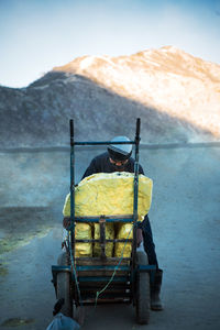 Man standing by rock in cart against mountain