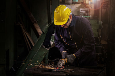 Worker welding metal in factory