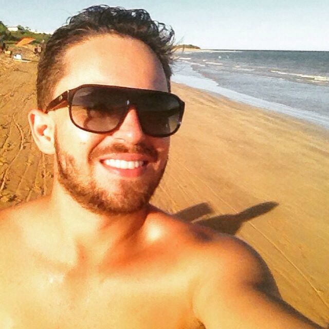 beach, person, portrait, lifestyles, young adult, looking at camera, sunglasses, sea, leisure activity, sand, water, young men, shore, headshot, front view, sunlight, vacations, smiling