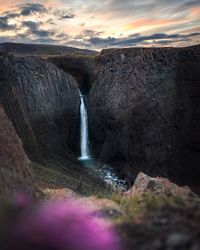 Scenic view of waterfall against sky during sunset