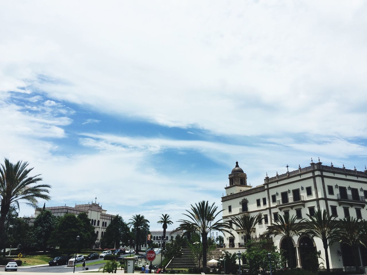 architecture, building exterior, built structure, sky, tree, cloud - sky, city, incidental people, cloud, cloudy, day, city life, low angle view, person, outdoors, travel destinations, facade, men, lifestyles